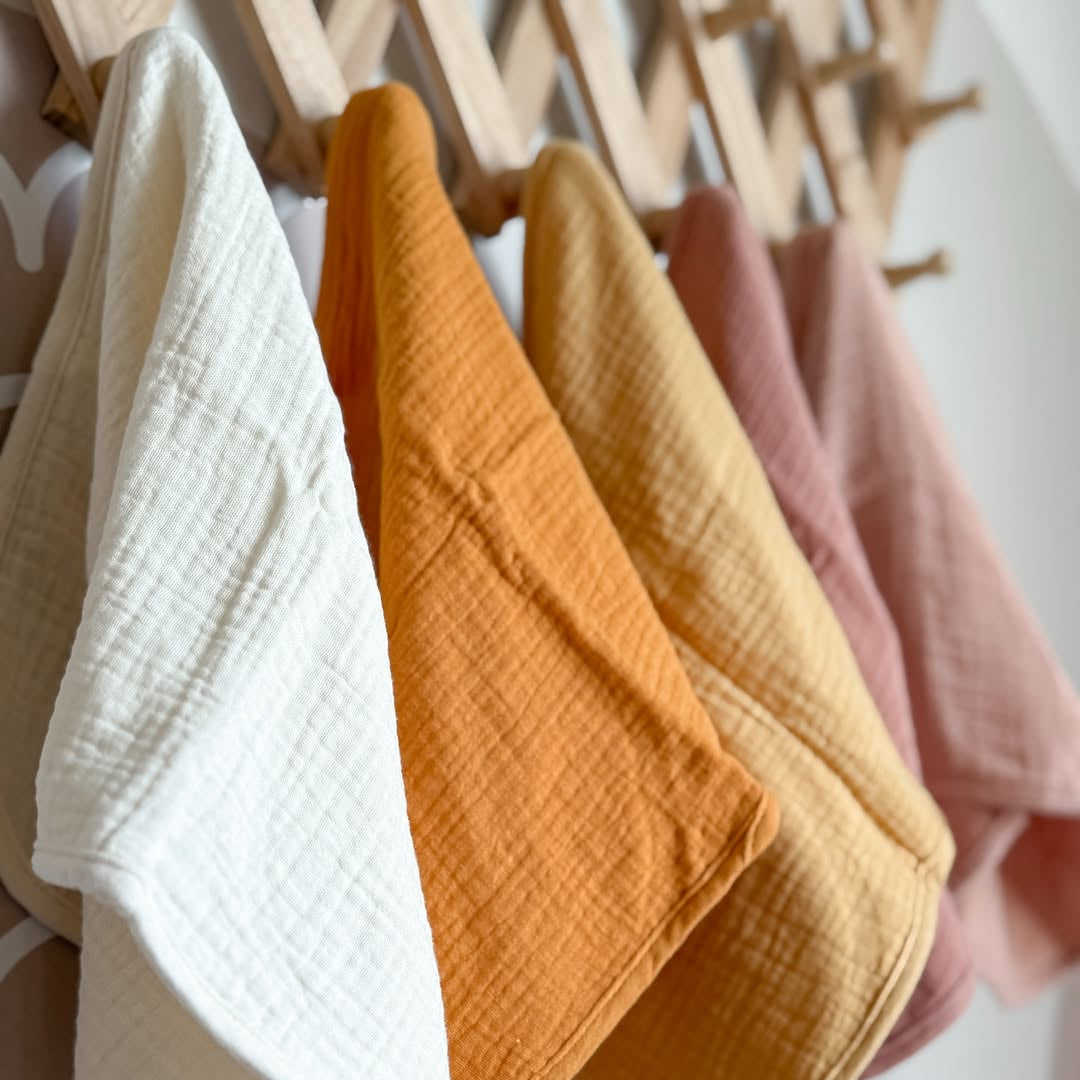 Five golden harvest organic muslin burp cloths folded and stacked together