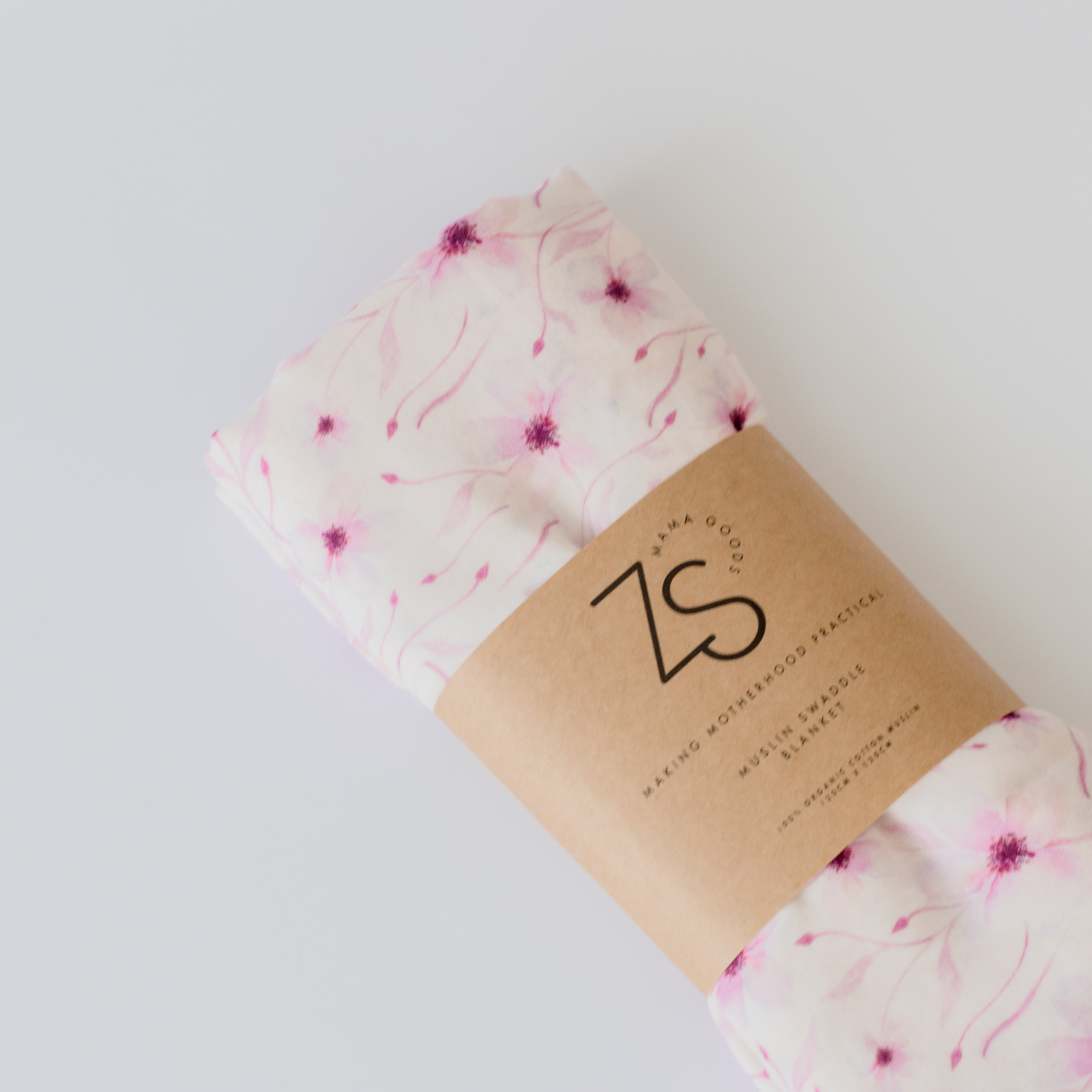 Organic cotton muslin swaddle wrap in soft blushing vine pattern draped gently.