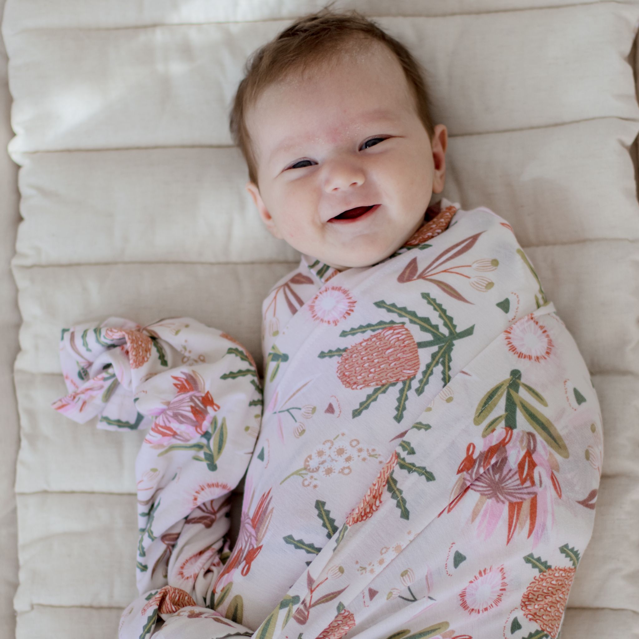 Stretchy baby swaddle wrap in gumnut blossoms pattern draped softly.