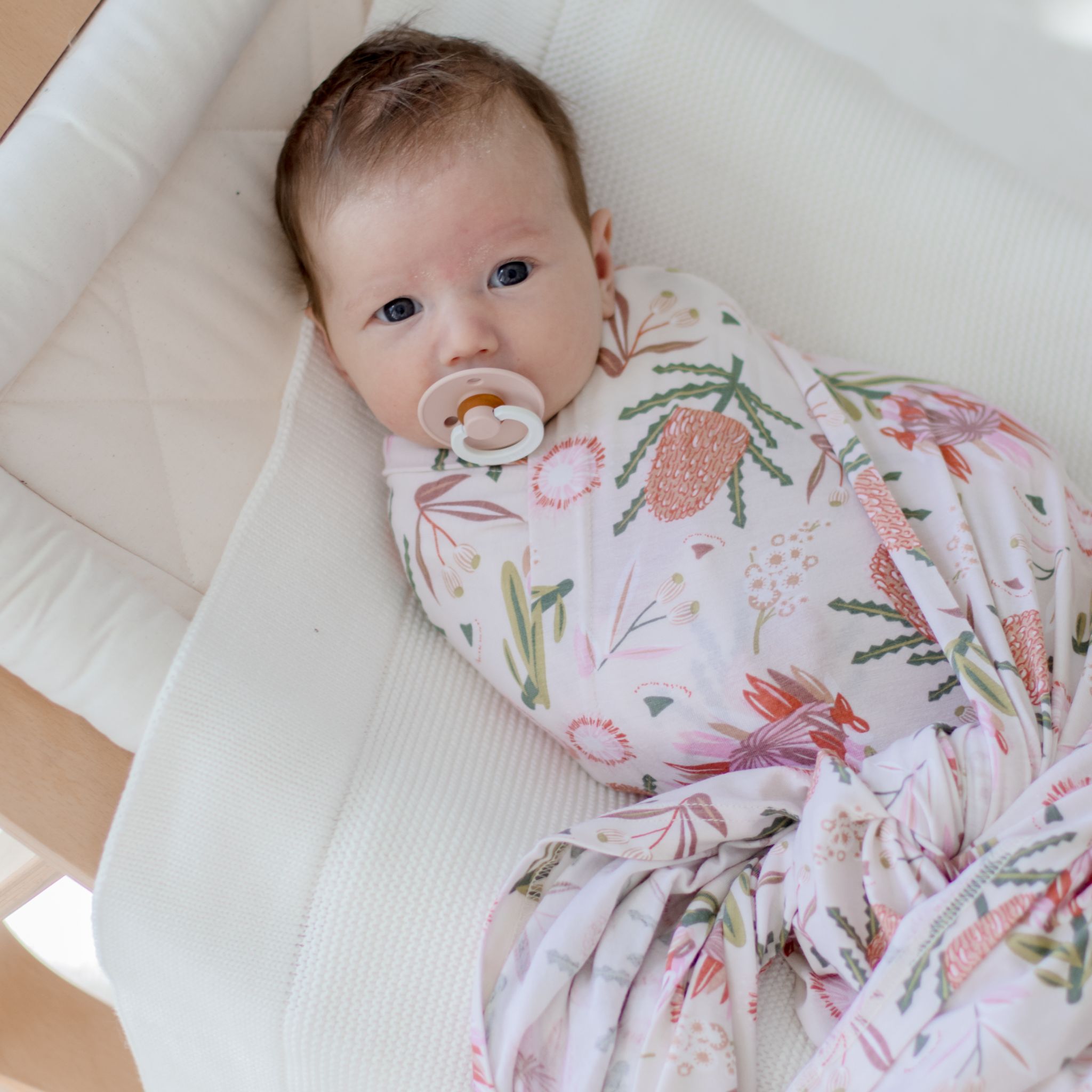 Cream stretchy baby swaddle wrap featuring delicate gumnut blossom print pattern