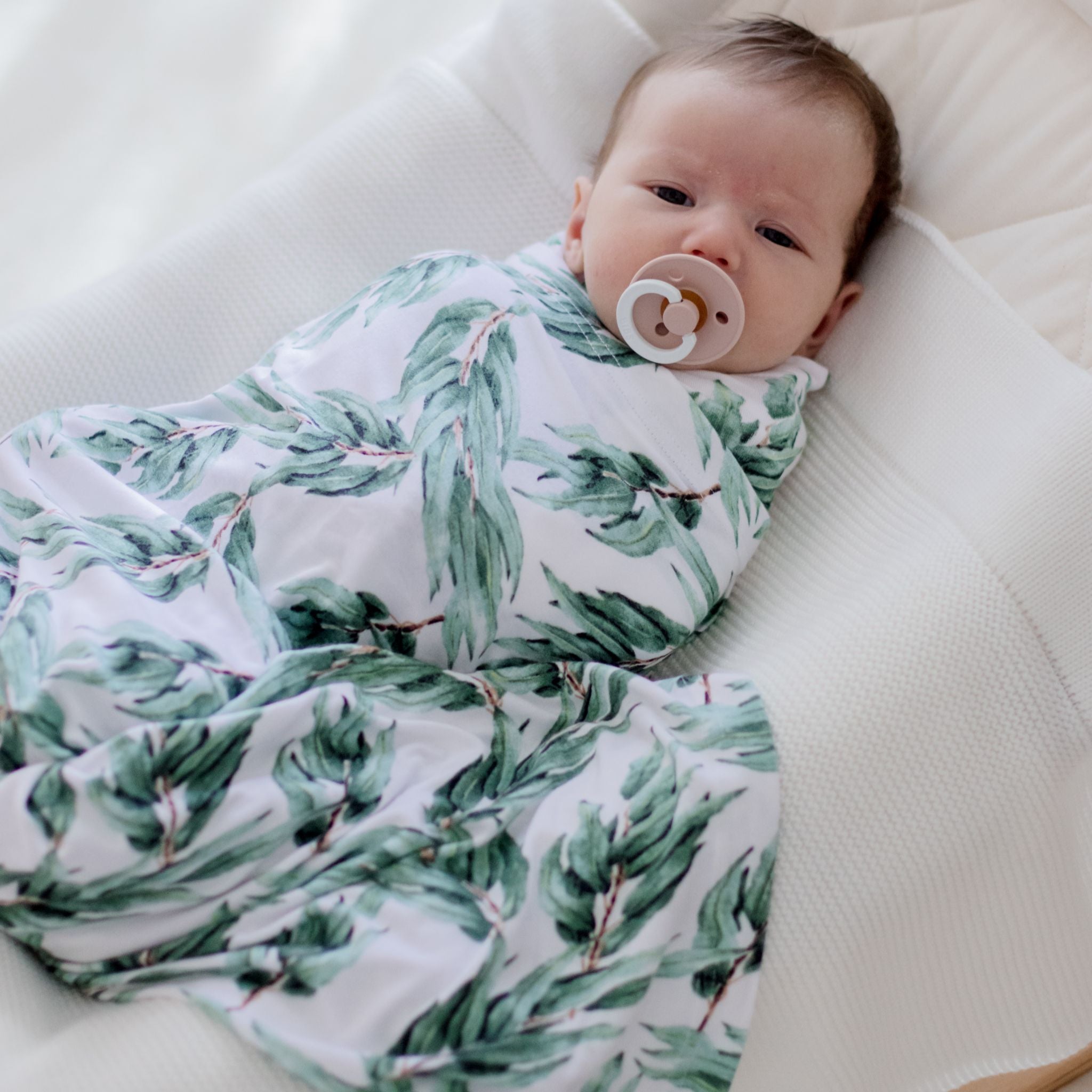 Stretchy blue gum leaf swaddle wrap wrapped gently around sleeping newborn baby