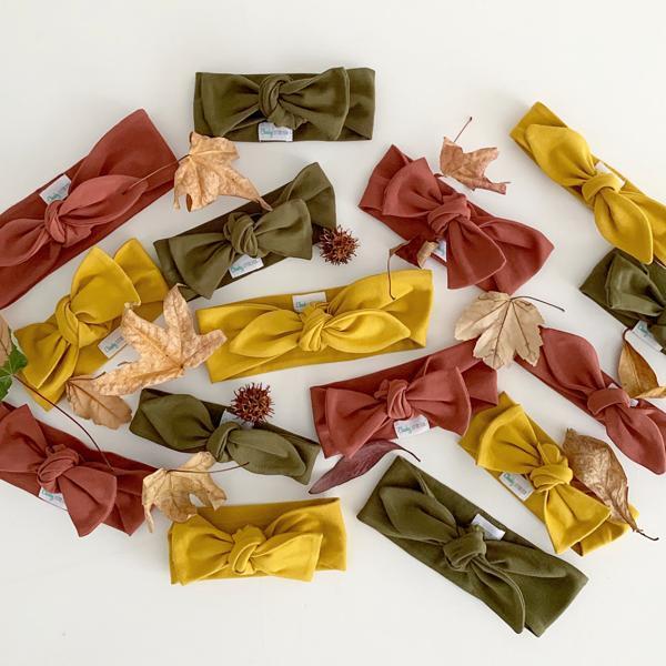 Rust coloured baby bow knot headband displayed in sustainable packaging