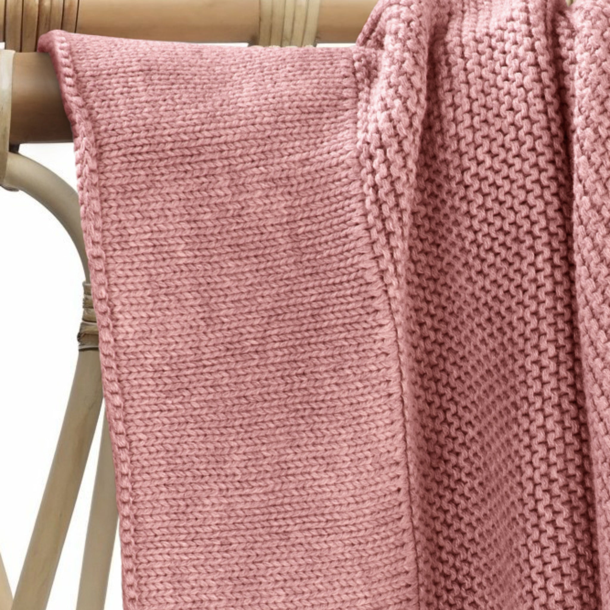 Soft plum cotton knit baby blanket draped over nursery furniture.
