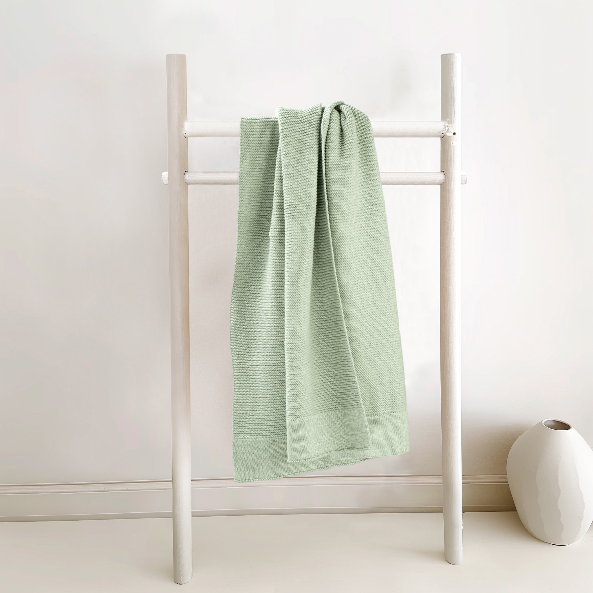 Folded willow green cotton knit baby blanket showing soft texture detail.
