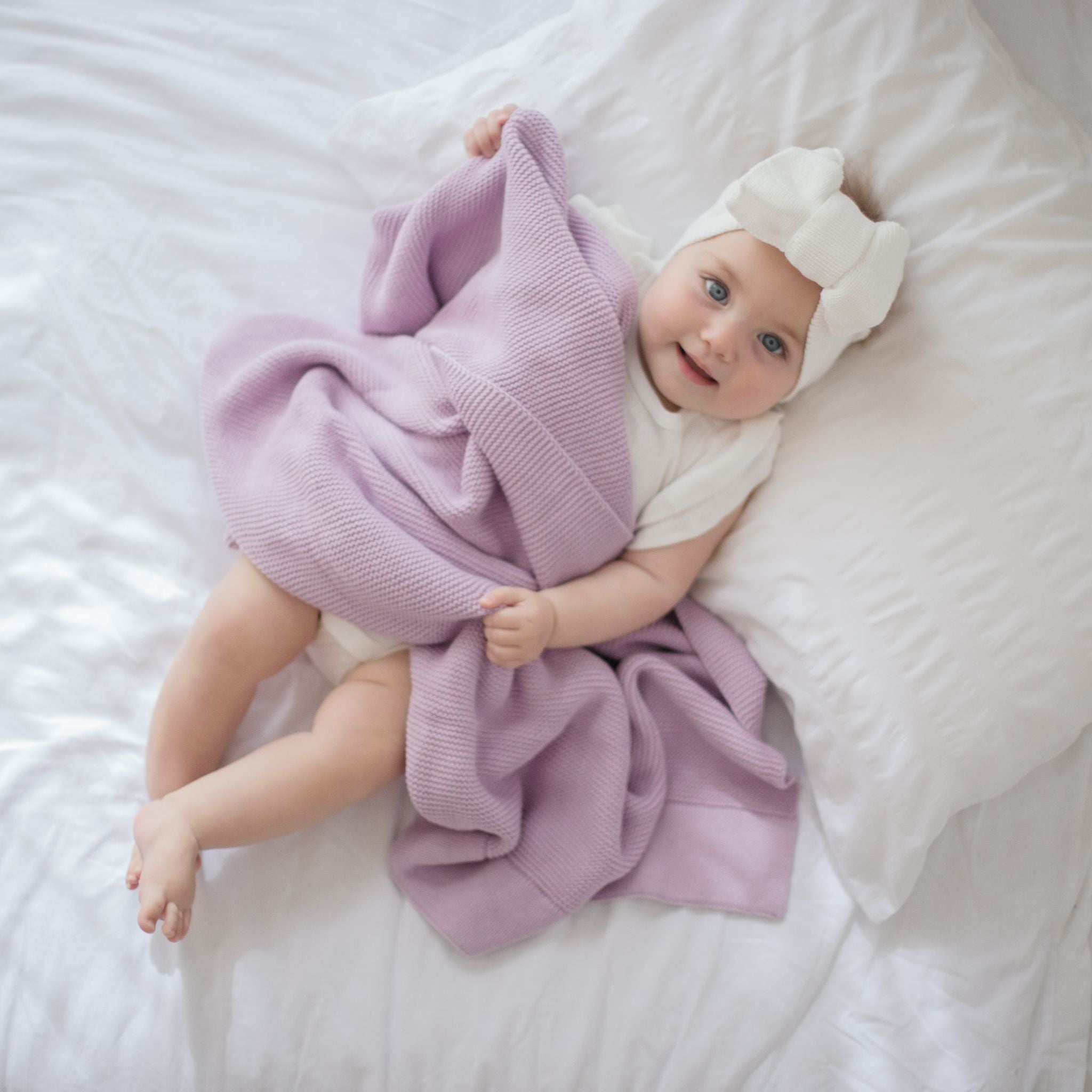 Cream knitted topknot headband styled on a baby model
