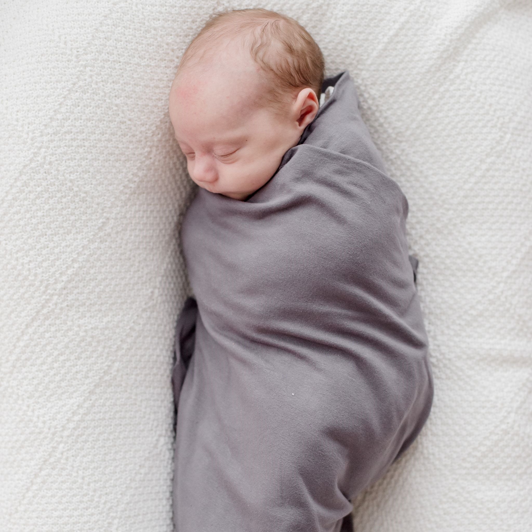 Stretchy baby swaddle wrap in storm grey organic fabric displayed folded