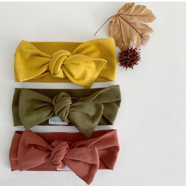 Rust colored baby bow knot headband on neutral background