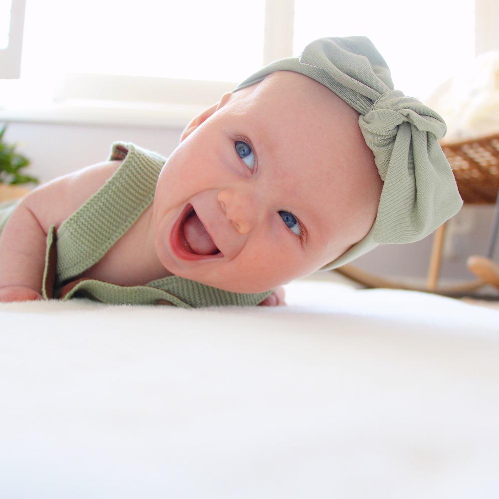 Sage green baby bow knot headband displayed on neutral background