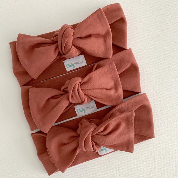 Rust coloured baby bow knot headband on infant, side view detail
