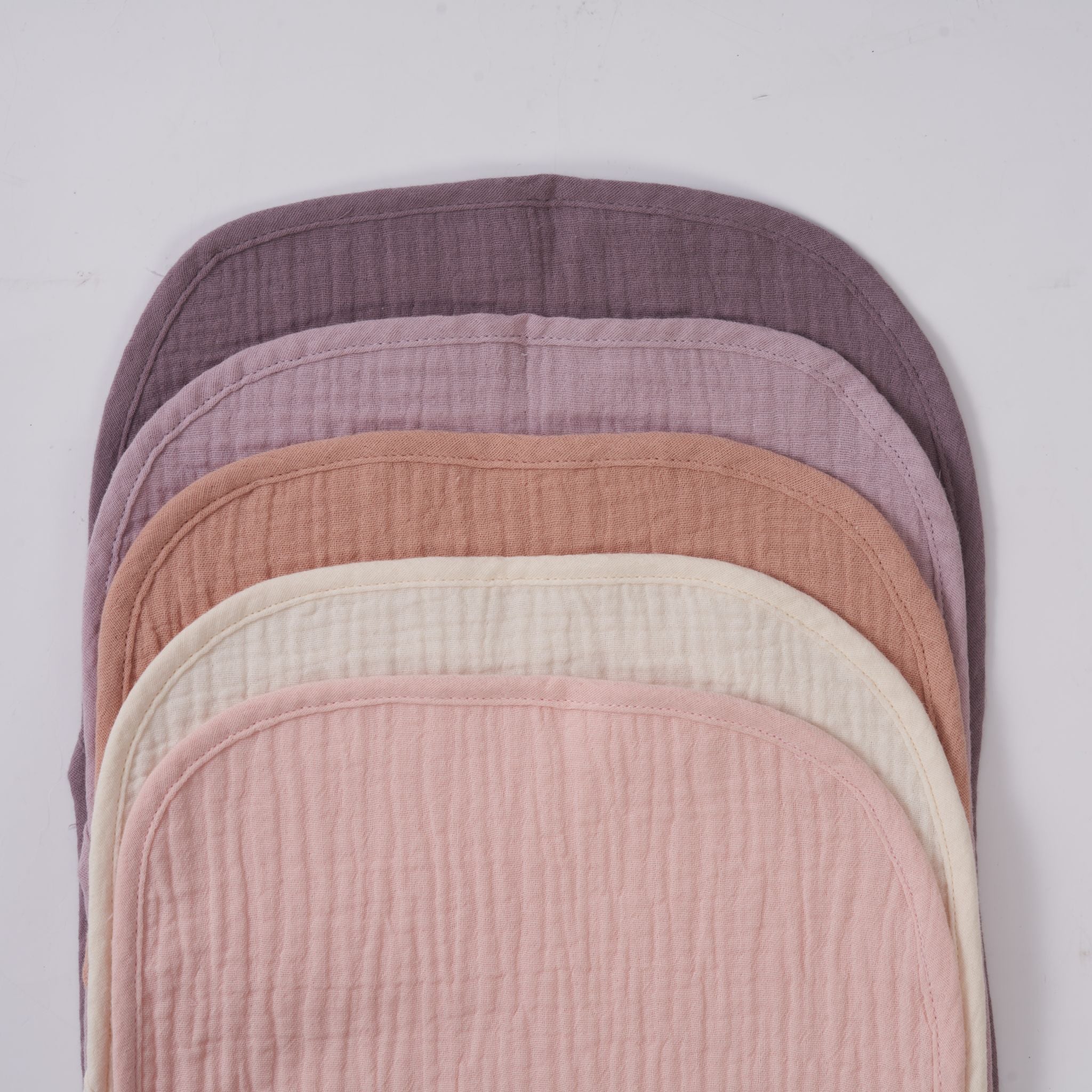 Soft organic muslin burp cloths in lavender blush pink displayed on baby.
