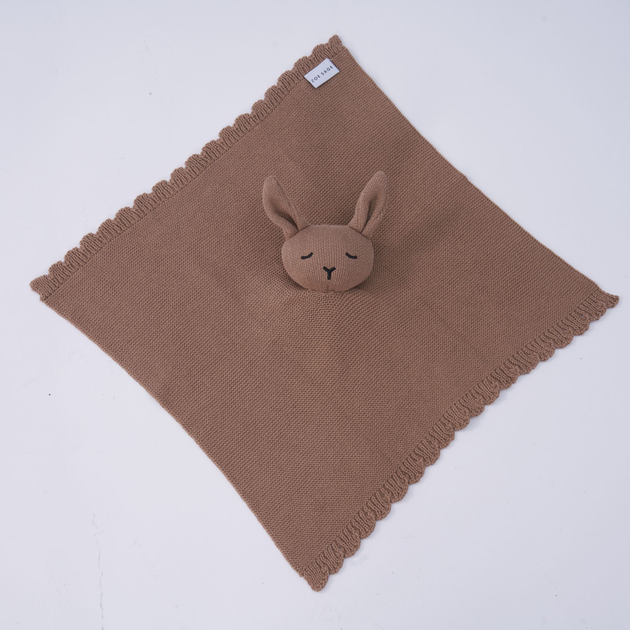 Soft mocha knitted lovey comforter draped over baby's shoulder during playtime.