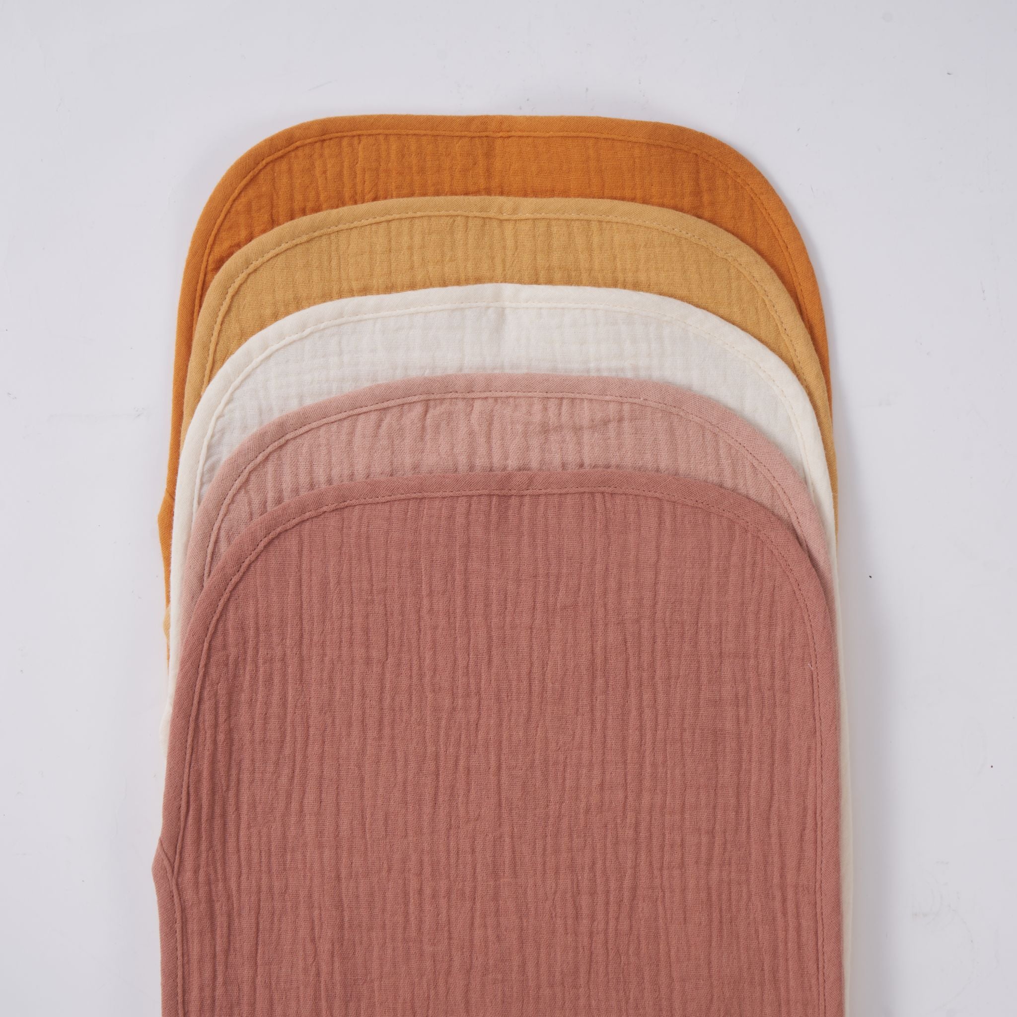 Organic muslin burp cloth in golden harvest tone draped over shoulder