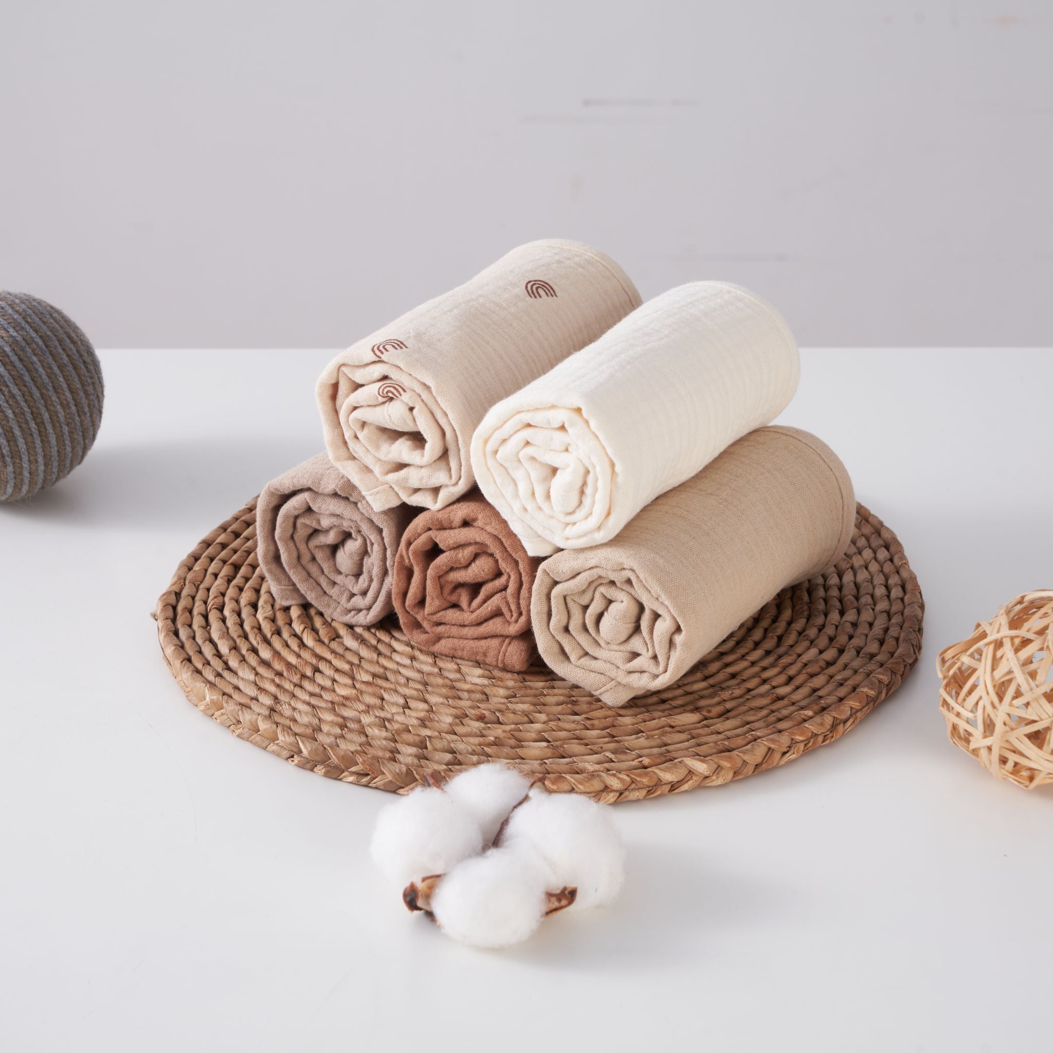 Five organic muslin burp cloths in dusty dune neutral tones stacked together