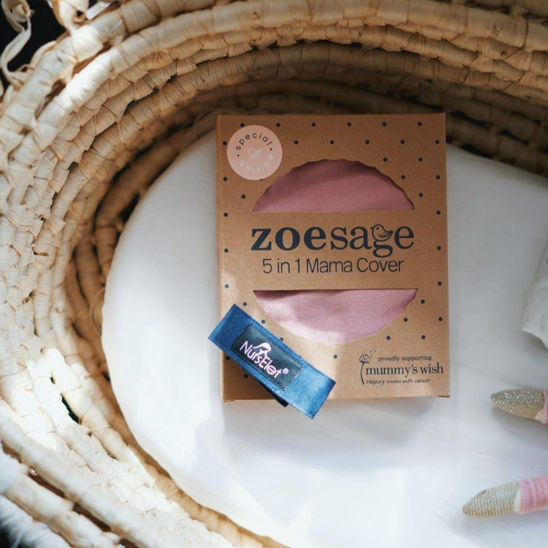 Dusty pink Zoe Sage 5-in-1 Mama Cover in a woven basket with a Nurselet breastfeeding bracelet